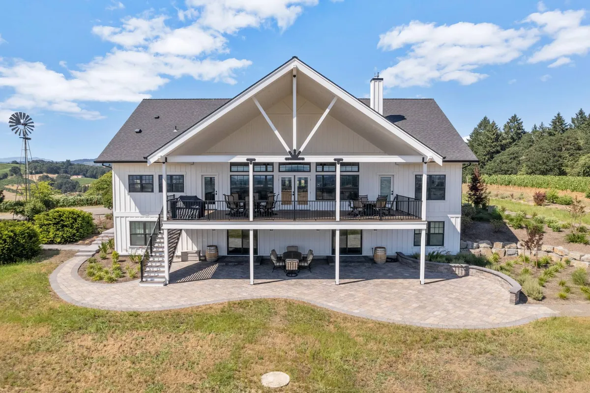 A large, charming porch wraps around the home, offering seating with views of the surrounding landscape and the property's windmill. The open outdoor space is ideal for group meals, conversation, and enjoying sunsets or stargazing in the evening.