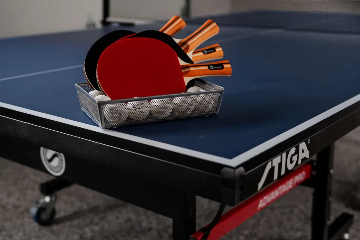 A close-up view of a ping pong table set for play, with rackets and balls ready on the surface. The cropped perspective emphasizes the competitive spirit and hands-on fun that defines the recreation space.
