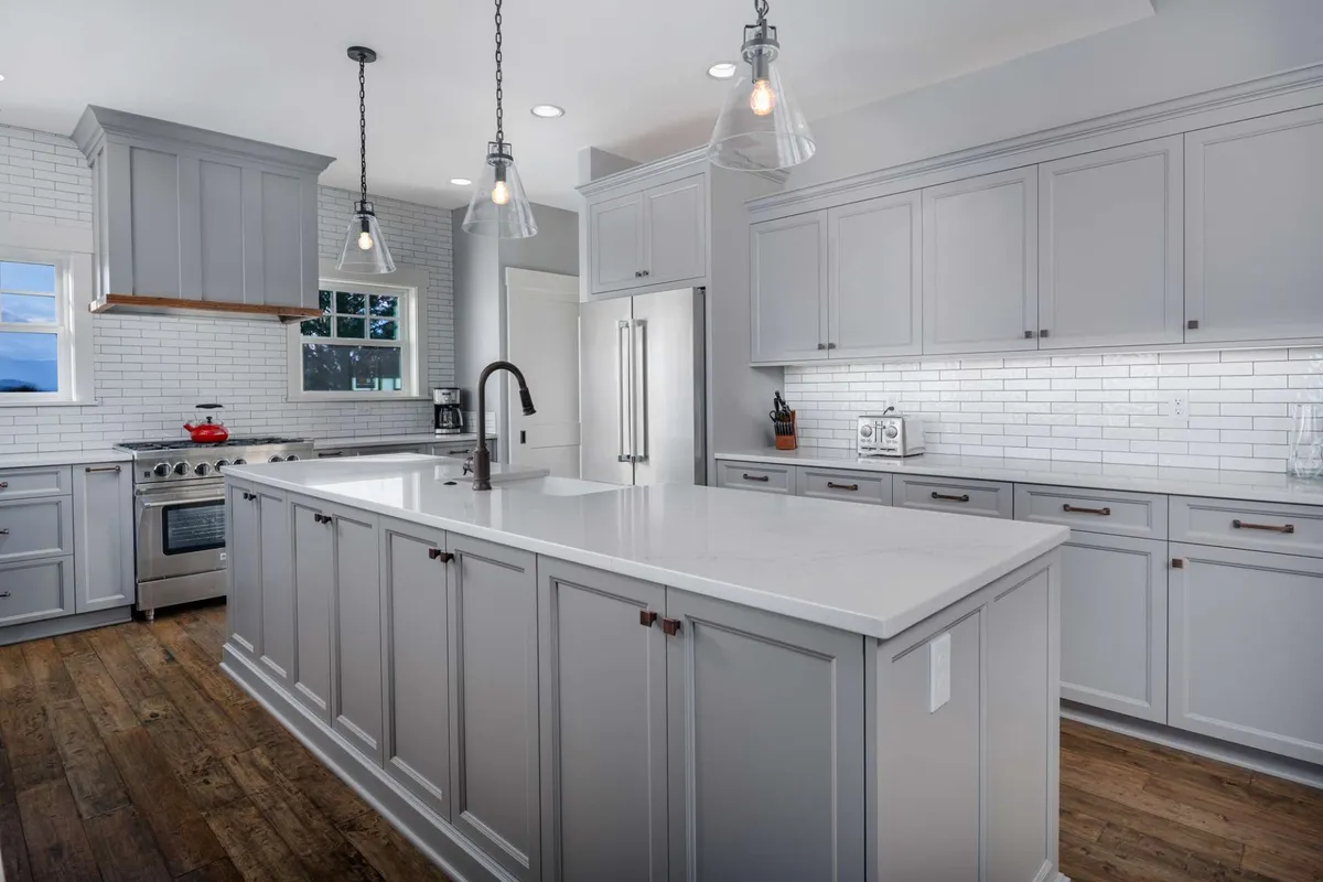 A bright, modern kitchen featuring a large island, stainless steel appliances, and stylish pendant lights. The open layout encourages social gatherings and culinary activities, while the cheerful atmosphere suggests a place for both relaxation and entertaining. Visible are settings that support activities like cooking, hosting a chef experience, or a family meal.